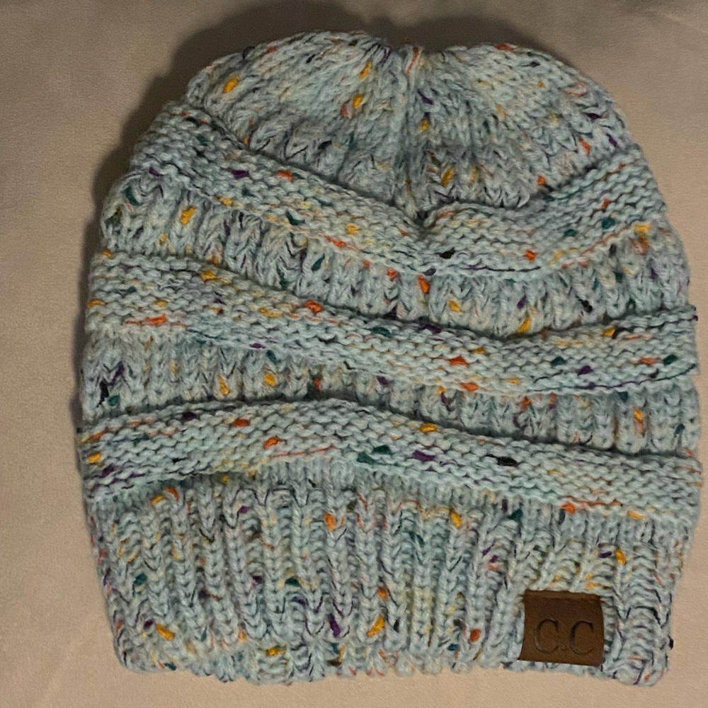Blue sweater knit beanie w/ponytail opening at top.